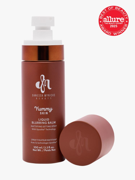 Danessa Myricks Yummy Skin Liquid Blurring Balm Powder Mattifying Setting Spray in branded copper bottle with spray closure on light gray background with red Allure Best of Beauty seal in the top right corner